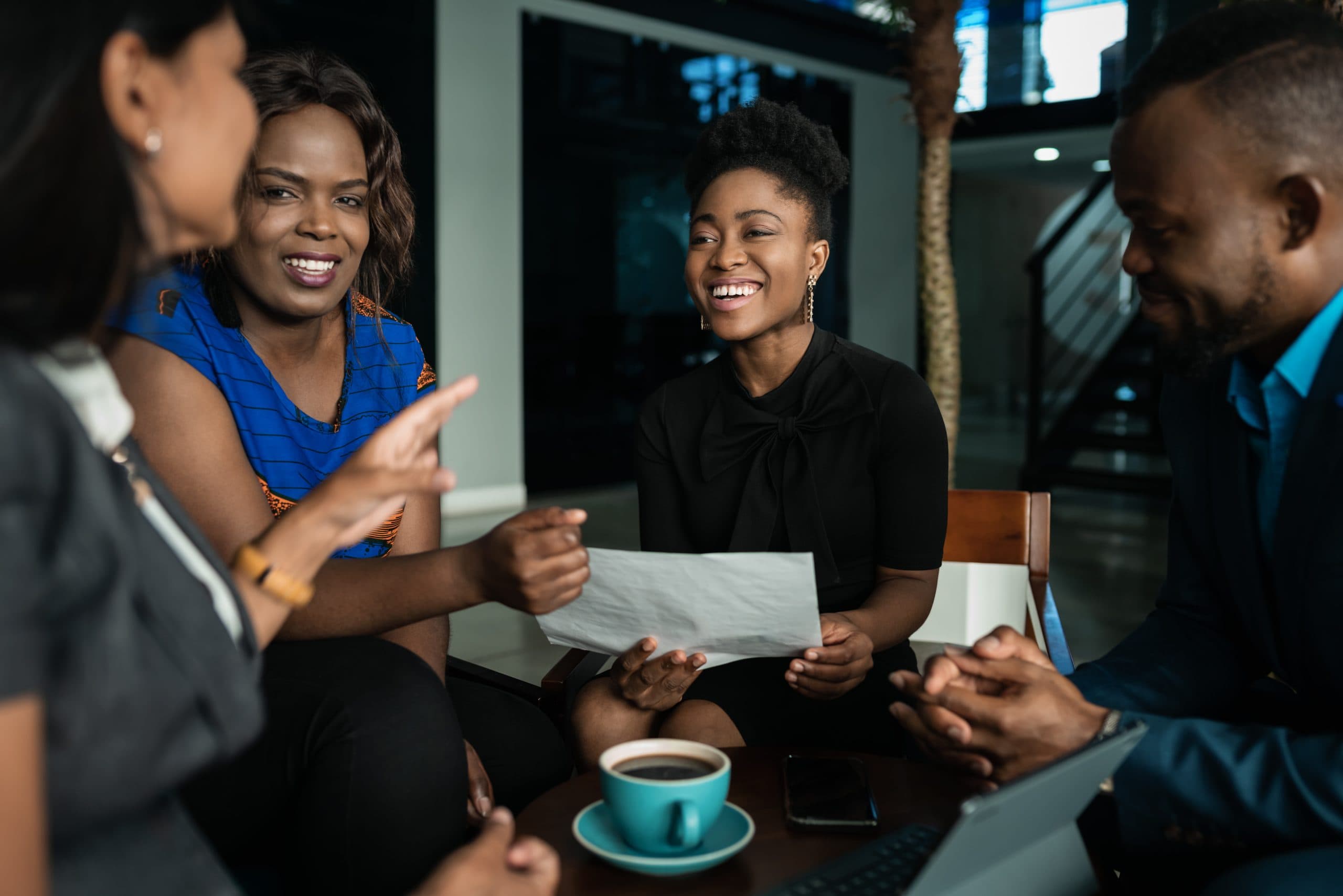 Young African businesspeople laughing together while going over paperwork